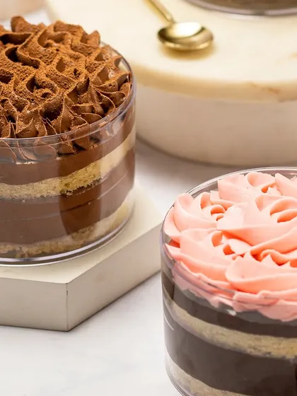 A close-up of my cake tubs available for Rakhi. You can see the rich Tiramisu tub and a whimsical pink-frosted cake tub, perfect for sharing with your sibling.