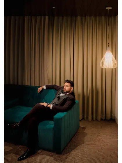 A stylish portrait of the groom, Santosh, looking dapper in his tuxedo during his reception. The moody lighting adds a touch of sophistication.