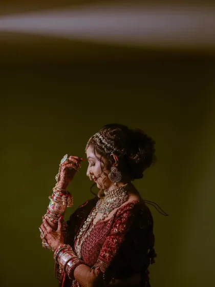 A side profile of the bride in a quiet moment, showcasing her intricate hairstyle and jewelry.