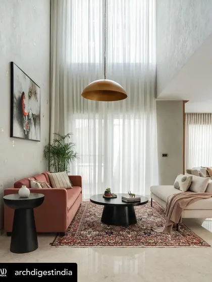A double-height living room in a modern family home designed by Weespaces, featuring our accent tables and chairs. The neutral palette is punctuated by our pieces, including a terracotta sofa and a caned accent chair, creating a warm and comfortable environment.