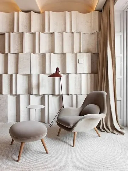 Comfort and sculptural form combine in this reading nook. The soft, curved armchair and the unique textured wall panels show how minimalism can be warm and inviting, creating a perfect corner for relaxation.