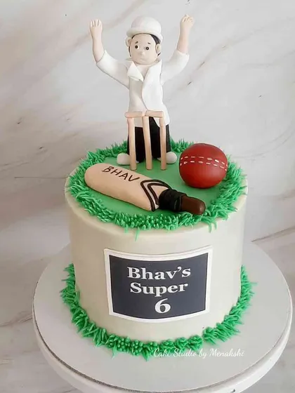A cricket themed cake for a 6-year-old's 'Super 6' birthday. The design includes a bat, ball, wickets, and an umpire, all handcrafted and edible.