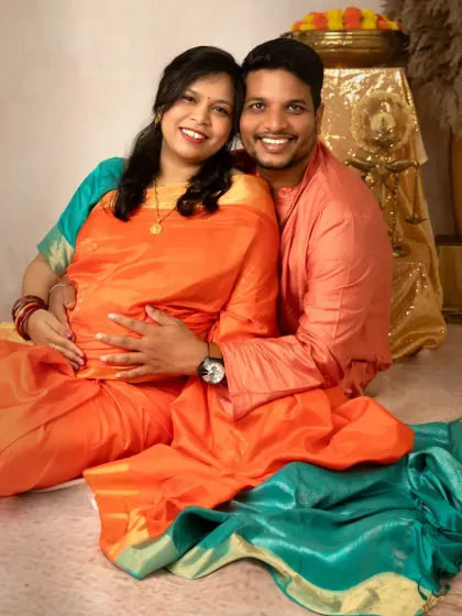 A happy, smiling portrait of the couple seated together. Their bright, coordinated outfits and joyful expressions perfectly capture the excitement of their pregnancy journey.