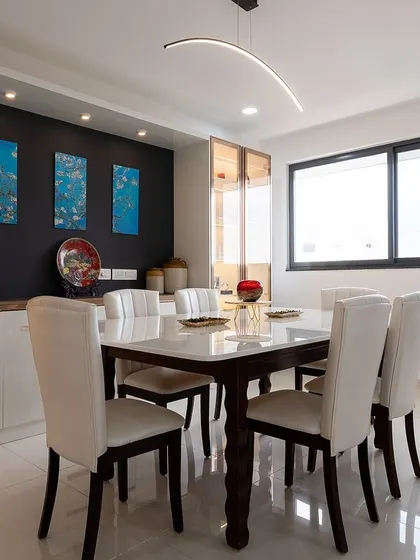 This modern dining room features a sleek table with white leather chairs set against a dark accent wall. The minimalist decor and contemporary lighting create a sophisticated and elegant dining experience.