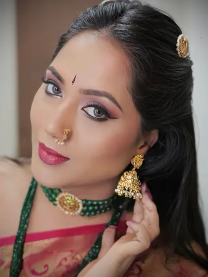 A close-up shot of a model, highlighting her dramatic eye makeup and traditional jewelry. Her direct gaze and confident expression make this a captivating beauty portrait.