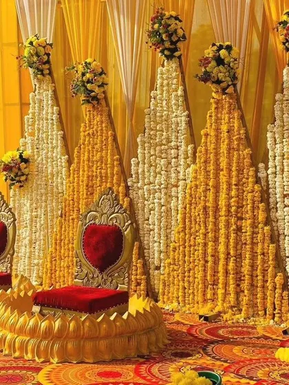 A closer look at our grand Haldi stage with heart-shaped chairs. The alternating panels of yellow marigolds and white tuberoses create a visually stunning backdrop for your event photos.
