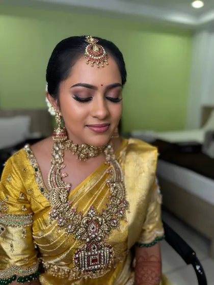 Vani with her eyes closed, showing the detail of her eye makeup. The blended brown and gold shades create a sophisticated and timeless look that complements her golden saree.