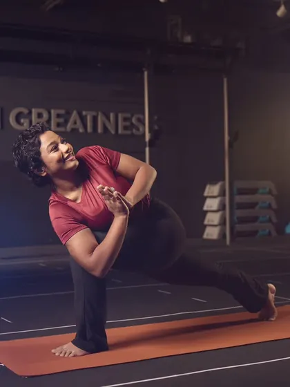 Holding the Parivritta Parsvakonasana, or revolved side angle pose. This posture challenges balance, strengthens the legs, and promotes spinal rotation, improving overall body coordination.