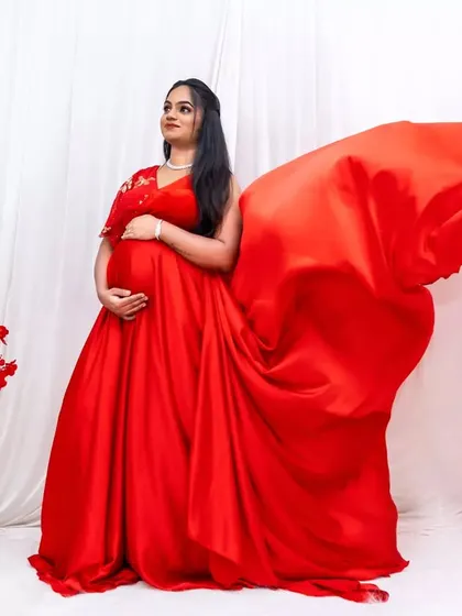 Make a bold statement with this fiery red maternity gown. The flowing trail adds drama and elegance to your photos.