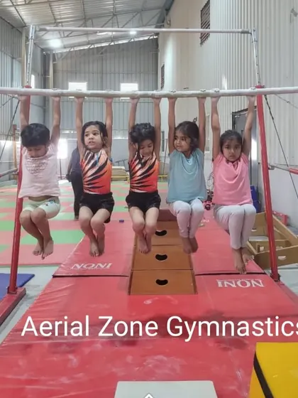 Even our youngest gymnasts learn the importance of strength. Here, they practice hanging from the bar to develop their grip and upper body strength.