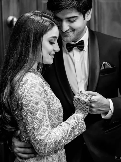 A classic black and white portrait that focuses on the couple's interaction and the beautiful textures of their outfits.