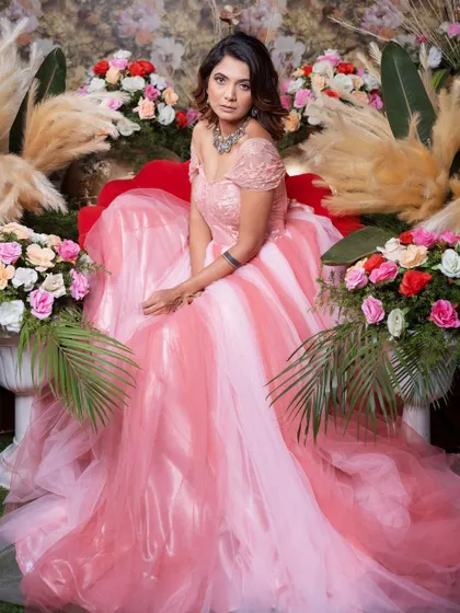 A wide shot showing the full splendor of the pink princess gown amidst a floral setting.