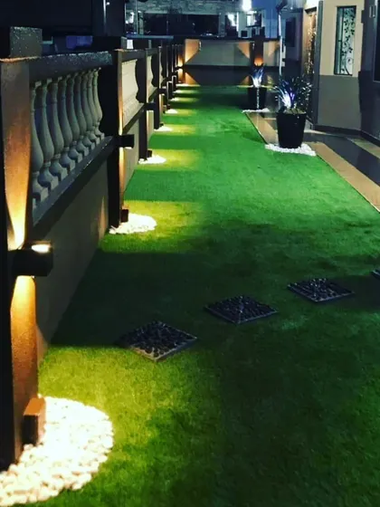 A rooftop walkway with artificial grass, stepping stones, and uplighting. This creates an elegant and functional path for evening use.