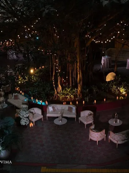 The outdoor lounge area for a reception, illuminated by fairy lights and candles. The elegant white furniture and surrounding greenery created a cozy and romantic space for guests to relax.