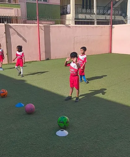 Our players line up for a drill, each with their own ball, ensuring maximum participation. This setup on an artificial turf pitch shows how we structure our classes to keep kids engaged and constantly learning.