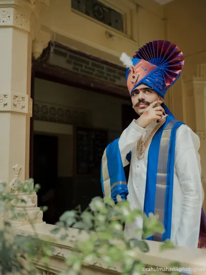 A handsome portrait of the groom looking out from a balcony, framed by greenery.