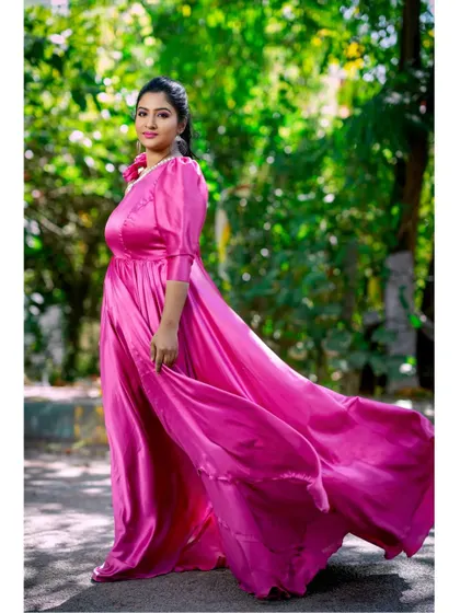 The movement of the pink satin gown's skirt adds a sense of grace and elegance to this outdoor shot.