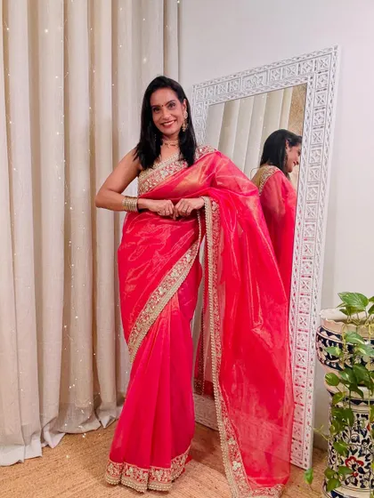This bright pink organza saree with an embroidered border is a beautiful choice for a wedding or a festive celebration. The color is vibrant and the fabric is lightweight.