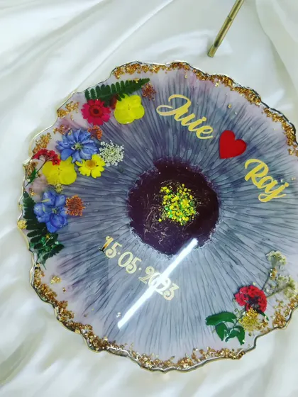 A beautiful customized resin table decor piece made for a newlywed couple. The purple textured base is decorated with colorful flowers and their names, creating a vibrant and personal gift.