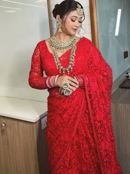 A full-length view of the red sheer saree, showing its delicate embroidery and elegant drape.