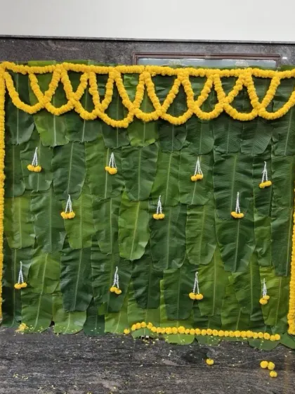 A simple and traditional backdrop created with banana leaves and small floral hangings.