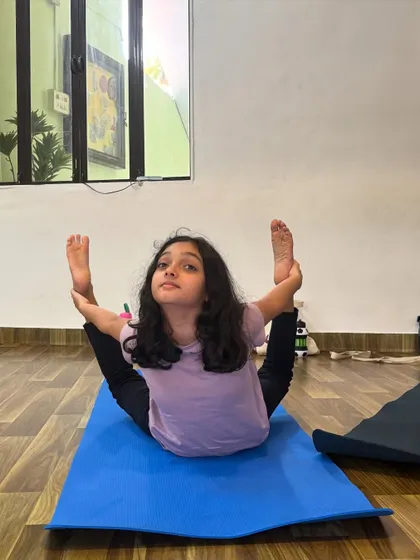 This young student shows incredible flexibility in this variation of Dhanurasana, or Bow Pose. Her dedication is inspiring.