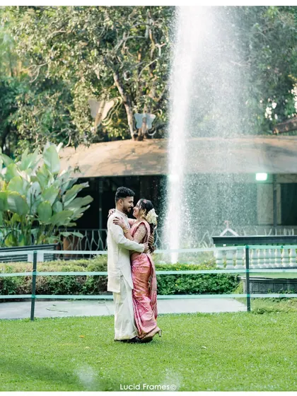 A wide shot of the couple in a garden with a fountain, creating a classic and romantic wedding portrait.