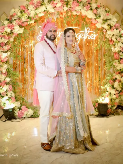 A classic wedding portrait in front of a stunning floral arch. The couple looks happy and regal, perfectly capturing the beauty of their special day.