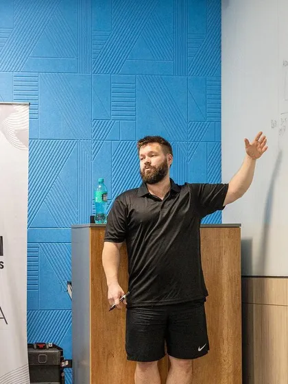 A trainer lectures on program design, pointing to a whiteboard filled with notes and diagrams during the UKSCA ASCT course.