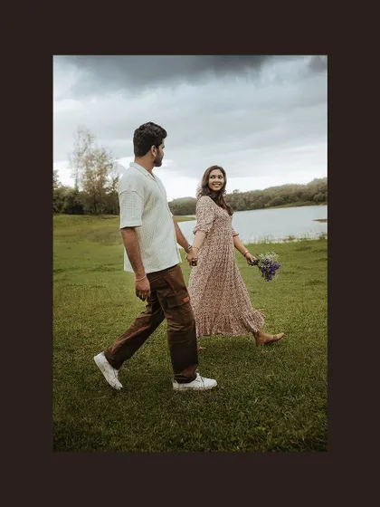 A simple and elegant shot of a couple walking hand-in-hand in a field by the lake.