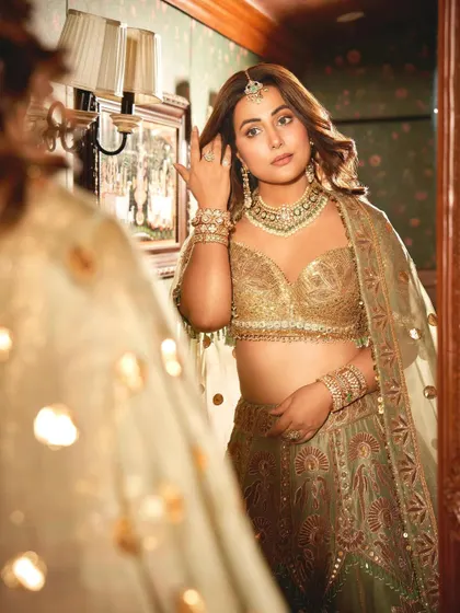 Hina Khan captured in a moment of reflection, adorned in a full JBR bridal look with a polki necklace, maang tikka, and stacked bangles.