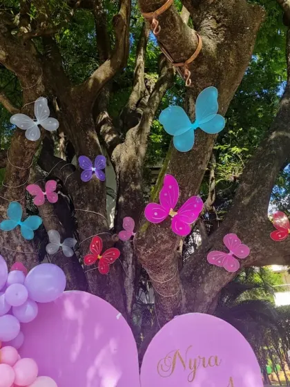 A close-up of the decorative butterflies attached to the tree, adding a whimsical touch to the outdoor party environment.