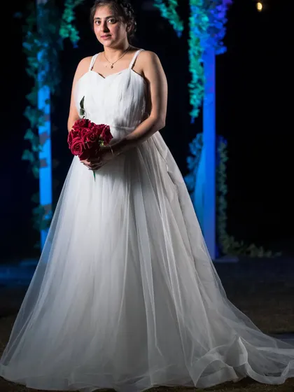 A portrait of a client in her custom-designed white wedding gown for a pre-wedding shoot. The simple spaghetti strap bodice and full tulle skirt create a classic, romantic bridal look.