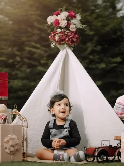 A sweet, candid moment during a first birthday celebration. The teepee and teddy bears create a cozy and playful backdrop for this little one's special day.