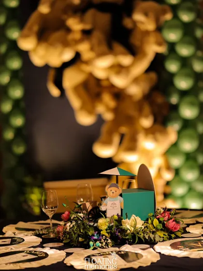 A whimsical installation of teddy bears appears to be climbing a wall next to a column of green balloons. This playful and eye-catching decor element was a favorite among both children and adults at the party.