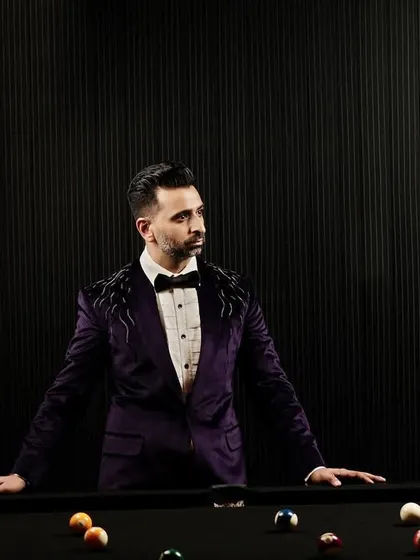 The deep purple velvet tuxedo stands on its own as a statement of refined taste. The dark, moody lighting emphasizes the luxurious sheen of the fabric and the intricate shoulder detailing.