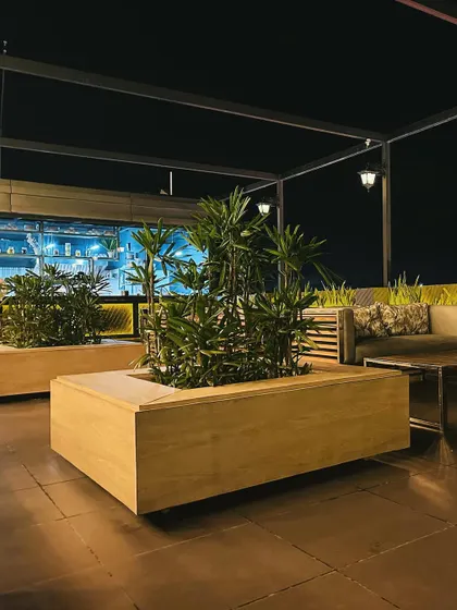 Large, movable wooden planters are used to define seating areas and add significant greenery to the rooftop terrace. This allows for flexible layouts while maintaining a lush atmosphere.