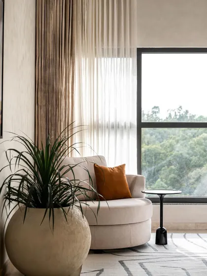 Warm minimalism envelops this understated master bedroom. We added a cozy corner hug chair to take advantage of the gorgeous forest view, creating the perfect Sunday vibe.
