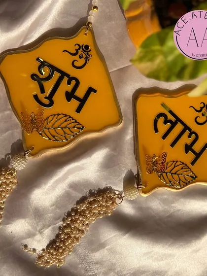 Welcome prosperity with these yellow 'Shubh Labh' hangings, featuring beautiful pearl tassels. Perfect for your home entrance during Diwali.