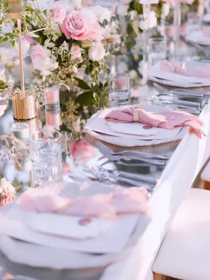 A close-up of the elegant tablescape at the 'Romantic Garden' reception in Bali. The mirrored tabletop, soft pink napkins, and delicate florals created a truly romantic atmosphere.