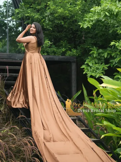This satin trail gown in a muted gold color offers a look of sophisticated elegance. The fabric has a beautiful sheen that catches the light as it flows down the stairs.