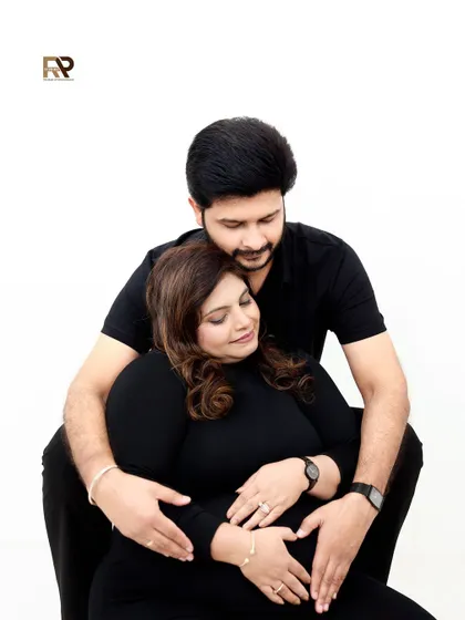 A loving embrace. This modern couple's portrait against a clean white background is all about their connection and the shared excitement for their new arrival.