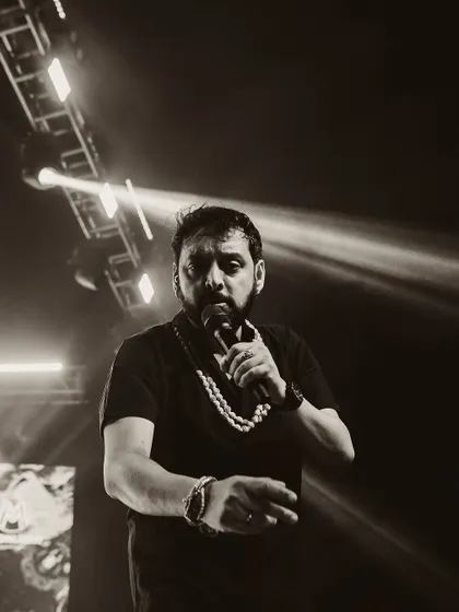 A singer on stage, captured in a moody black and white shot. The strong spotlight creates a dramatic contrast, focusing all attention on the performer.