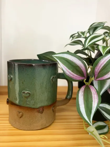 A sweet, hand-built mug with tiny impressed hearts, finished with a lovely green glaze.