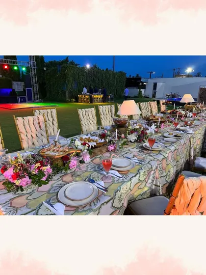 We also specialize in intimate, sit-down dinners. This image shows a beautifully decorated long table setup for an outdoor event, with floral arrangements and elegant tableware.
