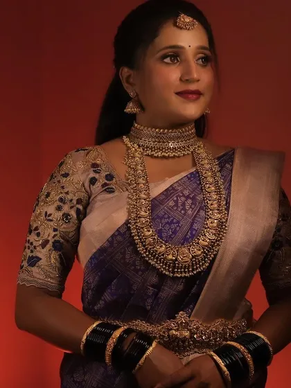 A model styled in a dark blue saree with a heavy antique gold choker and haram set, perfect for a grand event.