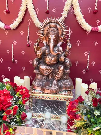 Blessings in every bloom. A divine Ganesha idol placed amidst red roses and candles, creating a sacred and beautiful corner at the wedding venue.