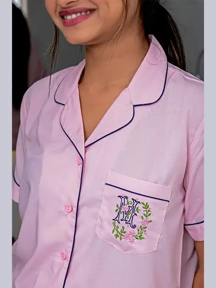 Highlighting personalization is key for many brands. This shot clearly displays the custom monogram embroidery on the pocket of a pink pajama shirt, a detail that is a major selling point.