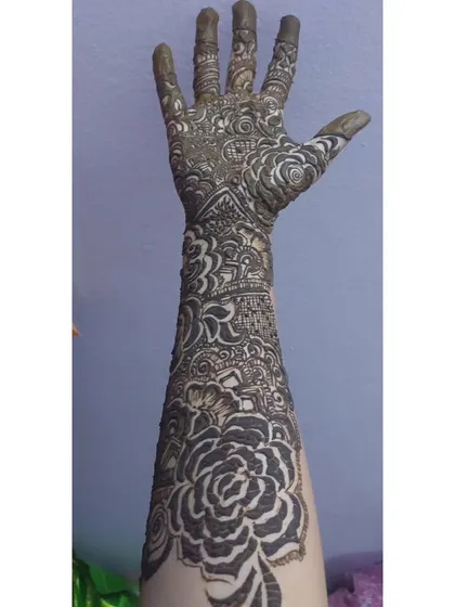 This front-on view highlights the symmetry and detail of the full arm design. Notice the fully covered fingertips, a classic element of bridal mehendi.