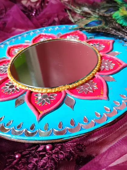 A vibrant 10-inch Lippan art mirror with a pink and blue lotus design, styled with peacock feathers.